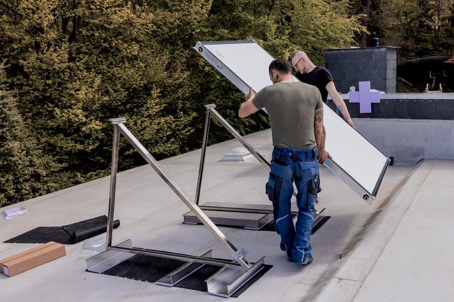 Zwei Heizungstechniker montieren eine Solaranlage